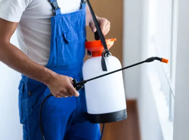 Pest control technician treating hotel property where termite bond and pest service compliance is tracked with RenewAlert