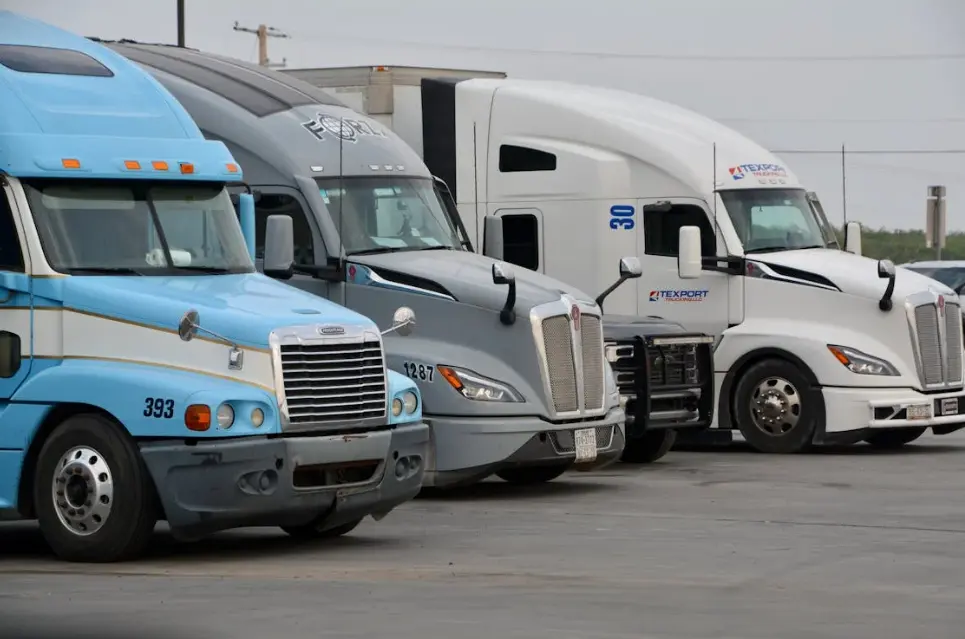 Row of semi trucks representing fleet DOT compliance checklist tracking with RenewAlert